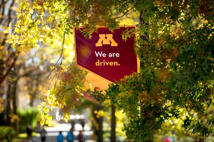 Red University of Minnesota flag with the words we are driven on it