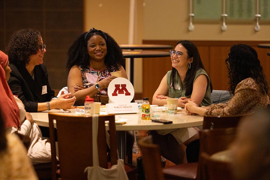 Staff, faculty, and students interacting at a table