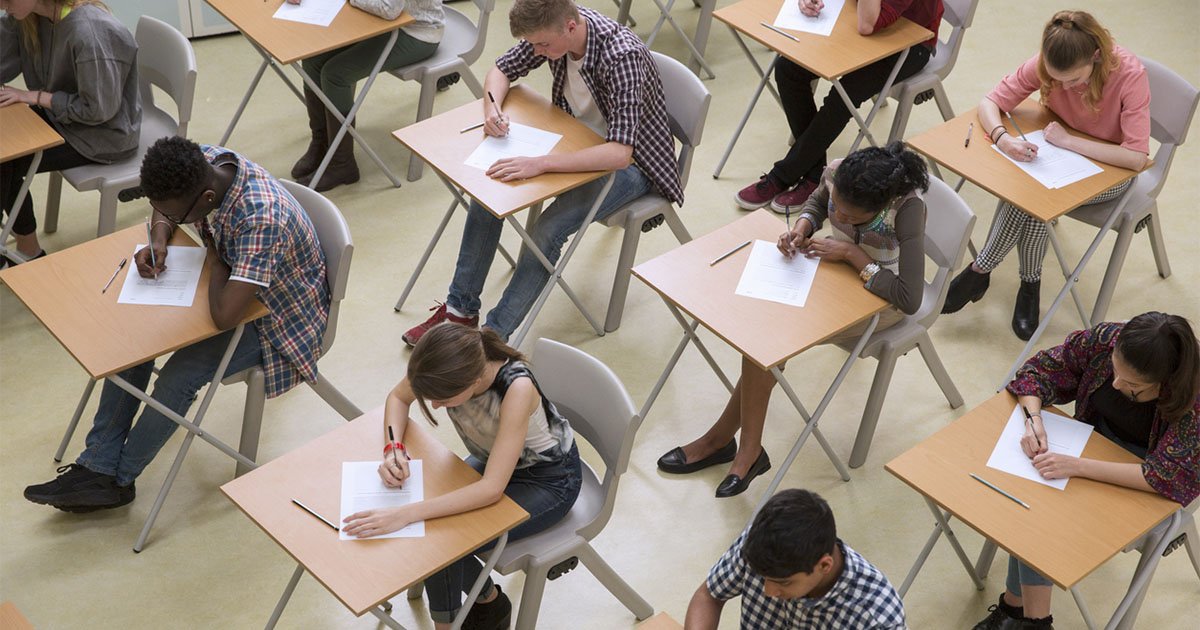 overhead view of several students at desks writing on white pieces of paper