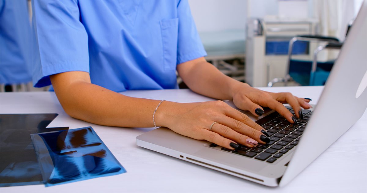 Woman in medical worker clothing typing on a laptop