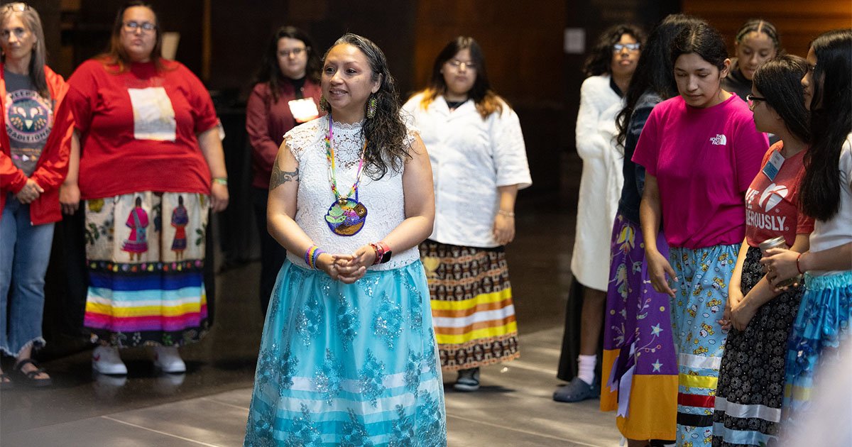 Several Native American people in traditional tribal clothing stand together