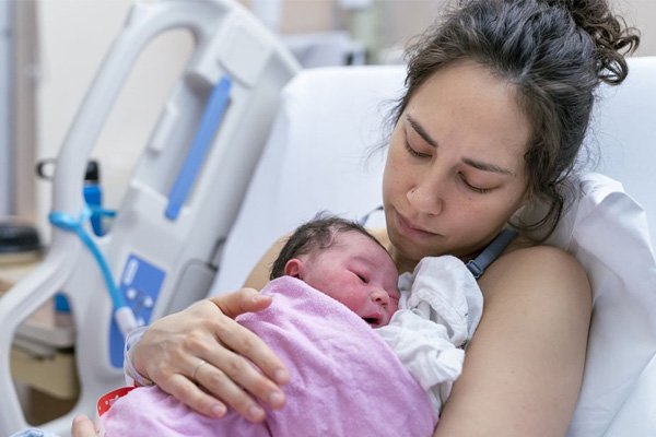 person with a baby laying in a hospital bed