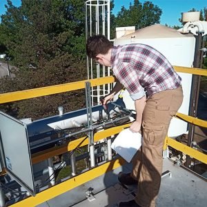 Person with back to camera working with a tool at an outdoor energy facility