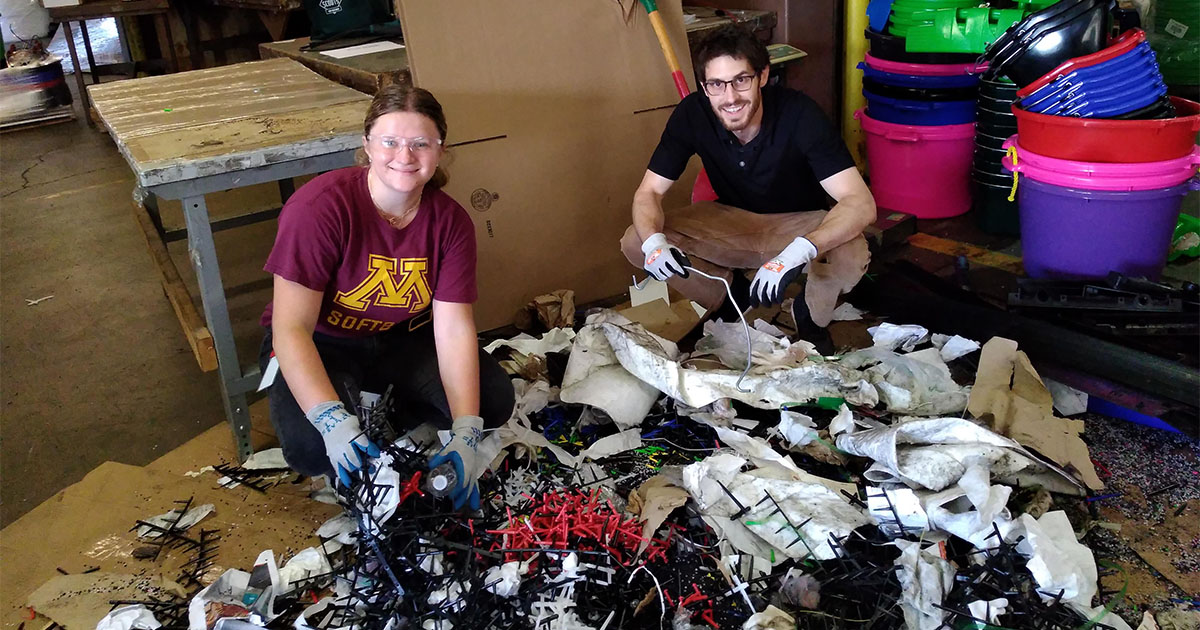 two people smiling while sorting trash