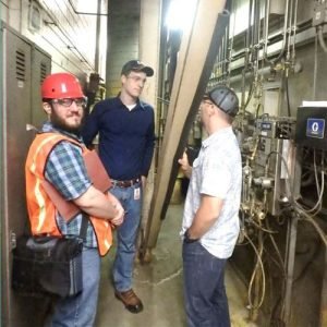 Three men standing talking to each other in an industrial facility