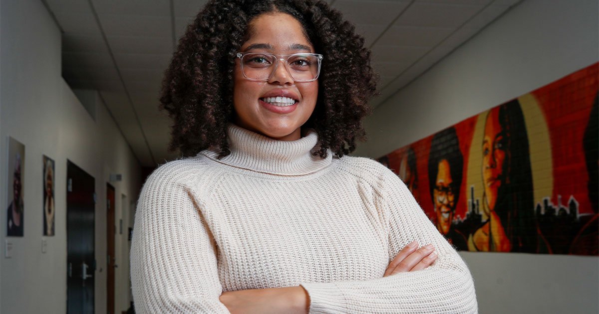 Dominique Earland, a Black woman, smiling with her arms folded in front of her