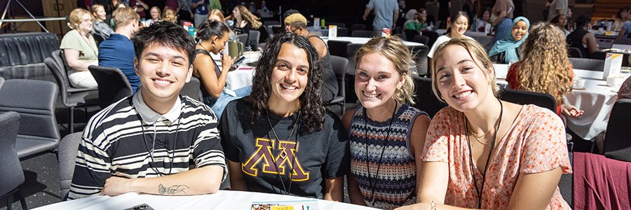 students smiling while sitting at table at orientation